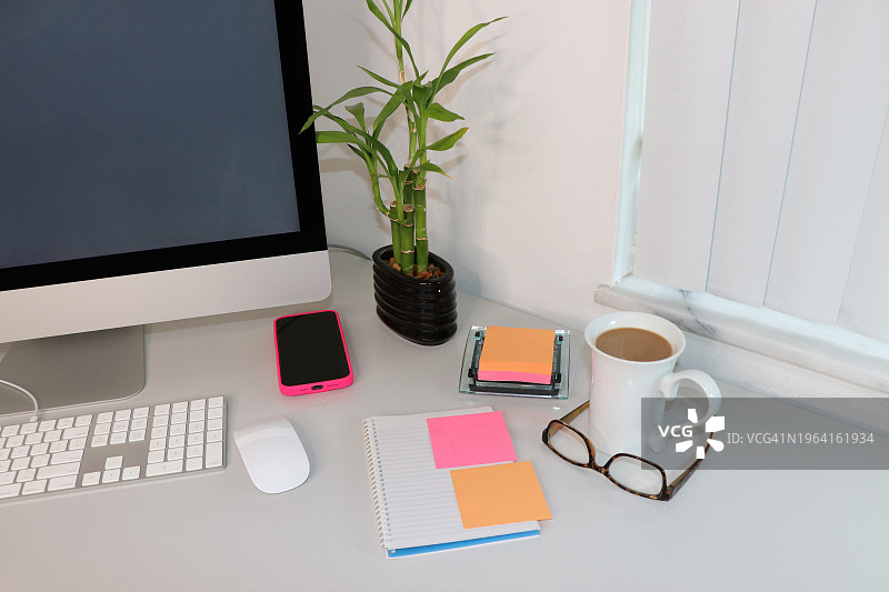 带竹子盆栽的现代办公桌上的彩色便签图片素材