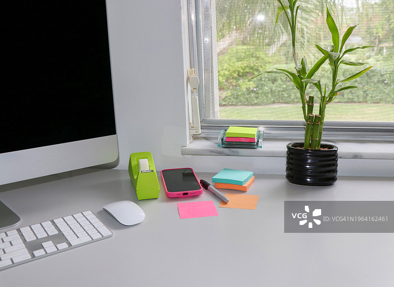 带竹子盆栽的现代办公桌上的彩色便签图片素材
