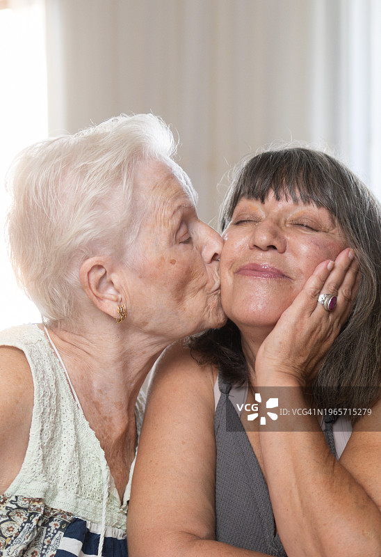 年迈的母亲亲吻年长的女儿的脸颊图片素材