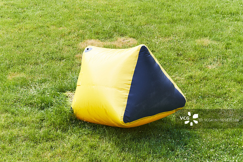 公园草地上放置的黄色充气垫图片素材
