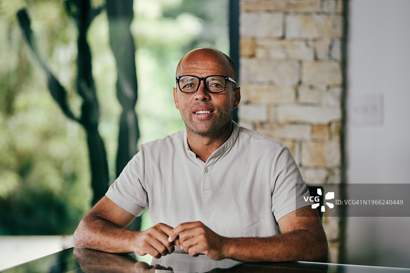 戴眼镜坐在露台桌旁的微笑中年男人图片素材