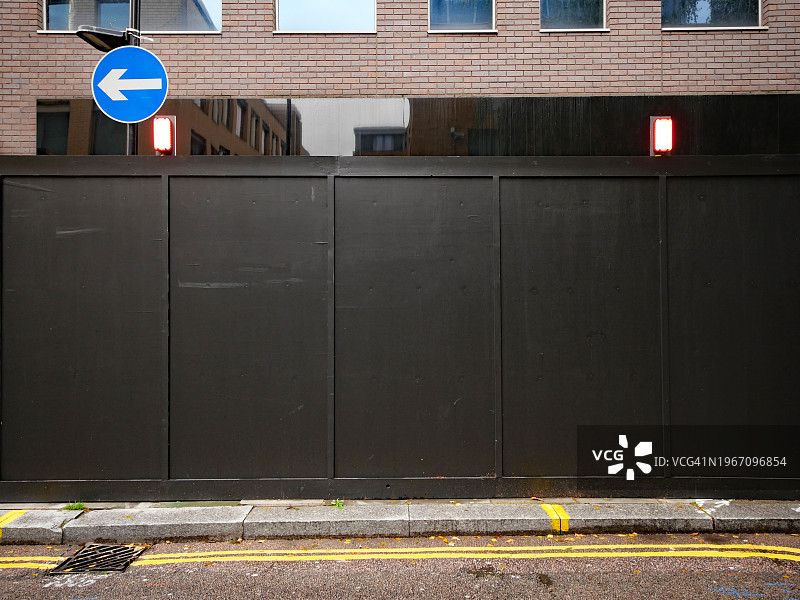 英格兰伦敦在建建筑物前的黑色油漆木板，带有道路标记的街道，阳光，自然色，无人图片素材