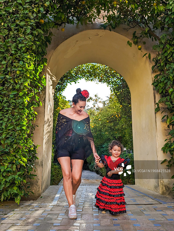 母亲和年幼的女儿在西班牙塞维利亚皇家阿尔卡萨花园穿着弗拉门戈服装图片素材