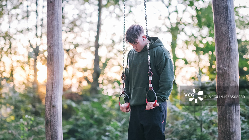 在森林里玩吊环的年轻人图片素材