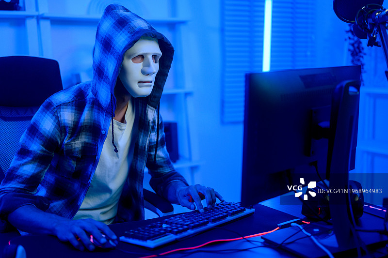 坐在电脑前戴着帽子的匿名人士图片素材