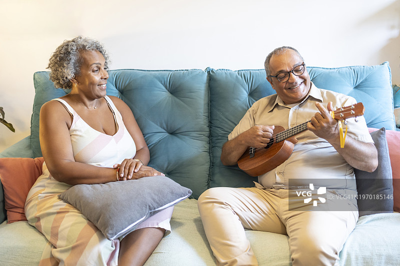 中年拉丁男子为黑人女子弹奏尤克里里图片素材