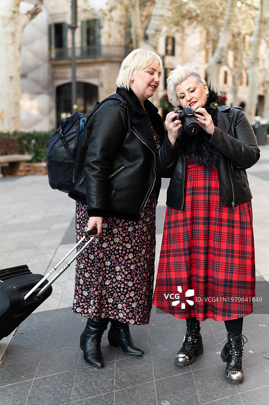 游客在街上手提行李箱用相机拍照图片素材