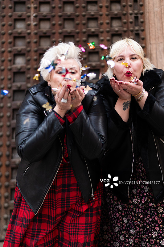 在街上吹着五彩纸屑的中年妇女们图片素材
