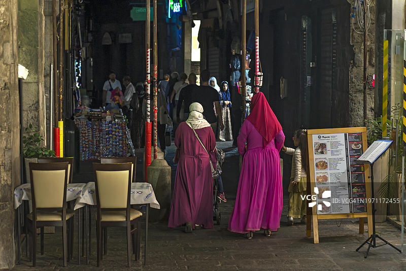 在意大利热那亚港口历史拱廊中身穿彩色长袍的女人图片素材