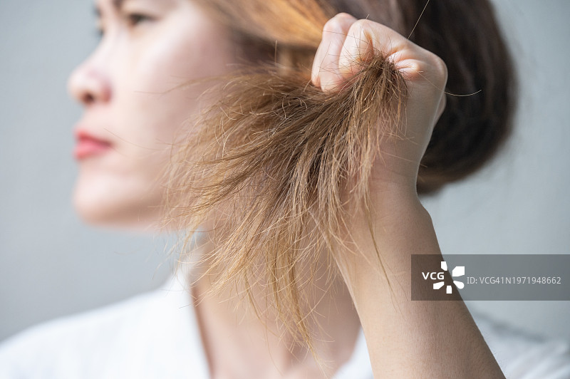 亚洲女性拿着凌乱分叉的头发图片素材