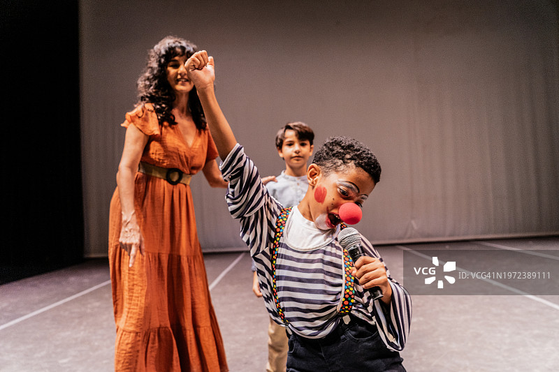 儿童小丑男孩在剧院舞台上唱歌图片素材