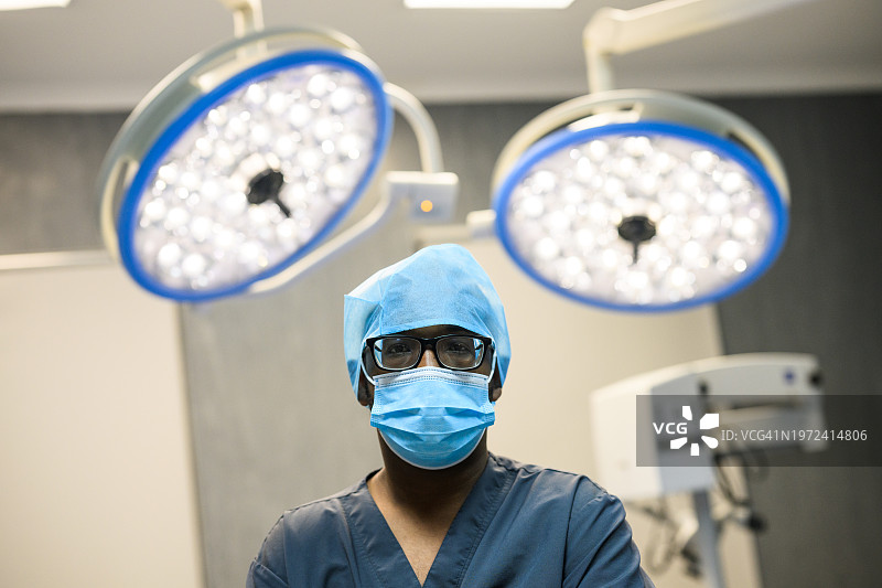 男护士站在手术室，背景是手术灯的特写图片素材