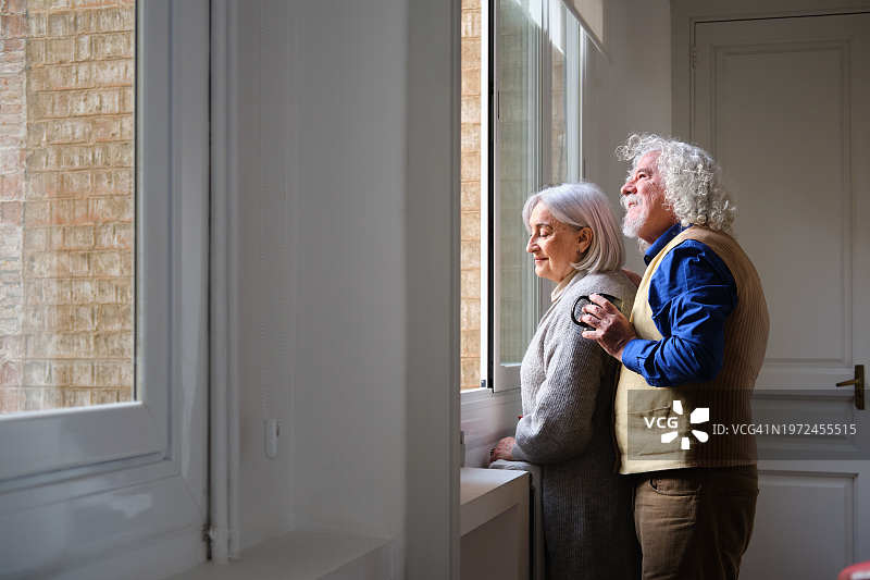 年长的白人夫妇在室内公寓窗口喝咖啡聊天的中景照片图片素材