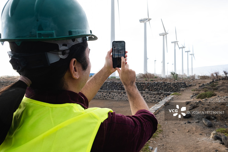 技术员用智能手机拍摄风力涡轮机图片素材