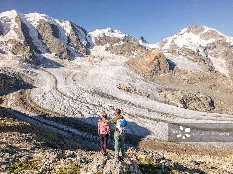 一对徒步旅行者在冰川上方的景色中眺望图片素材