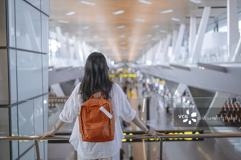 女子在购物中心二楼栏杆旁，手臂搭在围栏上眺望的背影图片素材