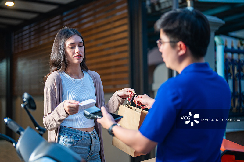 年轻女子使用信用卡进行线上购物和支付手机费用。图片素材