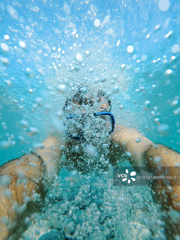 戴着面罩在水下气泡中游泳的游泳者图片素材