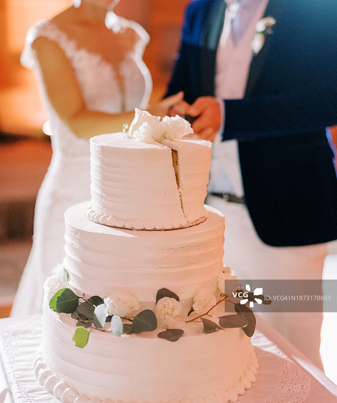 婚礼仪式上，新娘和新郎拿着结婚蛋糕的腰部图片素材