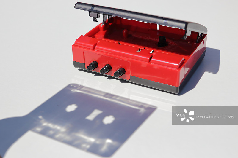 白色桌子上带有磁带阴影的红色卡式播放器图片素材