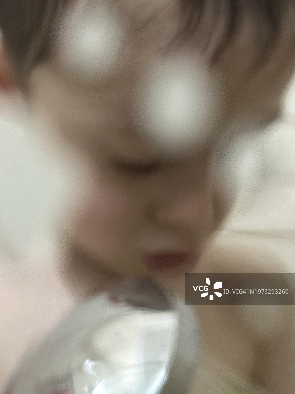 淋浴后，一个三岁男孩洗着脸，带着有趣的意图看着镜头图片素材