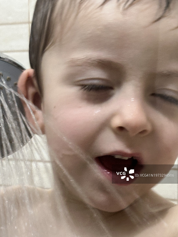 淋浴后在浴室里洗脸和玩水的三岁男孩图片素材