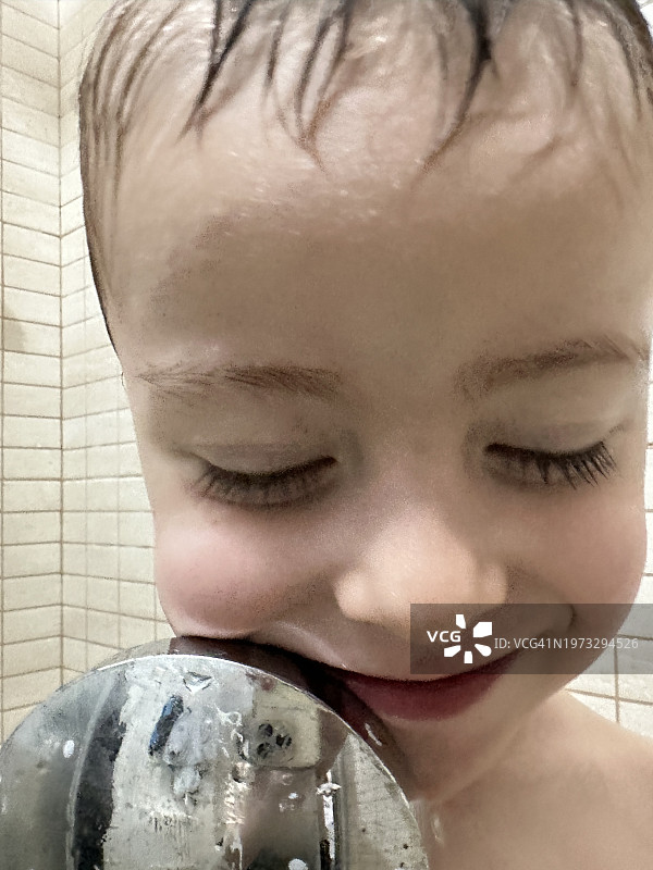 淋浴后在浴室里洗脸和玩水的三岁男孩图片素材