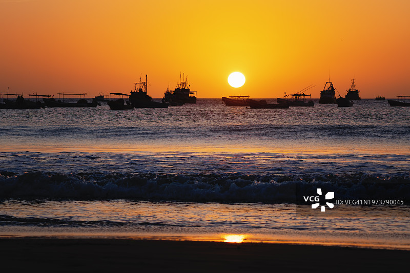 海平面上太阳与剪影船只的金色日落图片素材