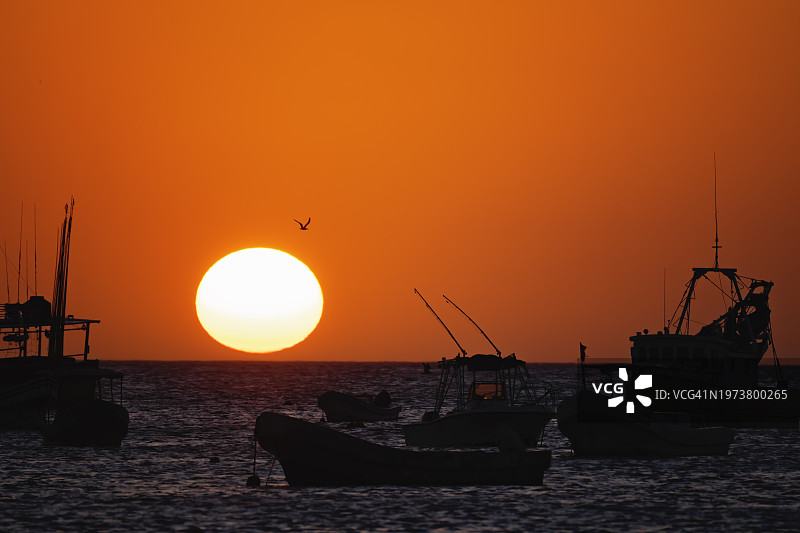 海平面上太阳与剪影船只的金色日落图片素材