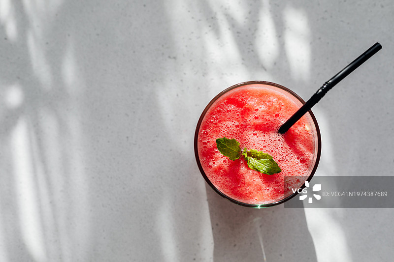 浅灰色桌子上盘子里玻璃杯中的西瓜饮品，夏季饮品图片素材