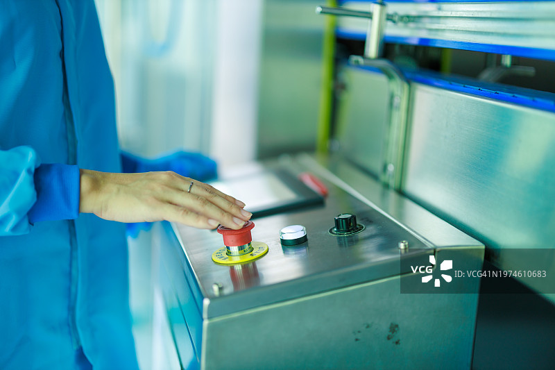 亚洲女工迅速按下生产线上的紧急停止按钮，确保安全图片素材