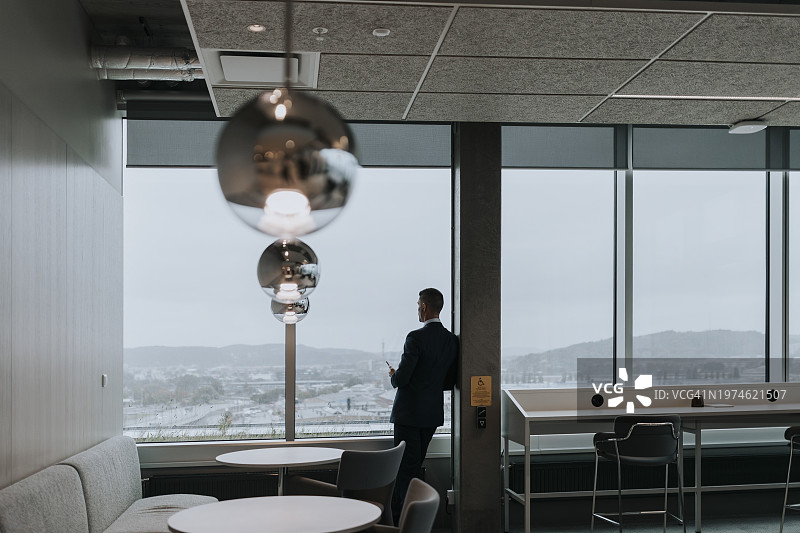 商务人士在办公室透过窗户向外看的背影图片素材