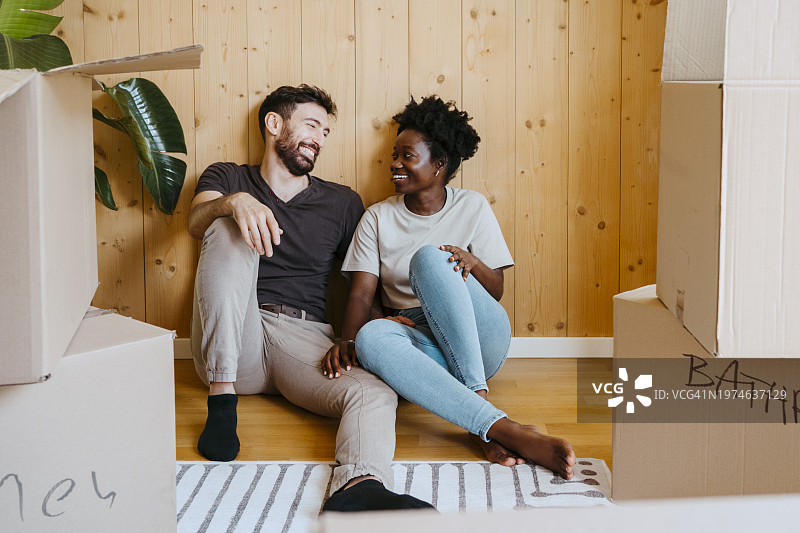 快乐的多种族夫妇在新家木墙边聊天图片素材