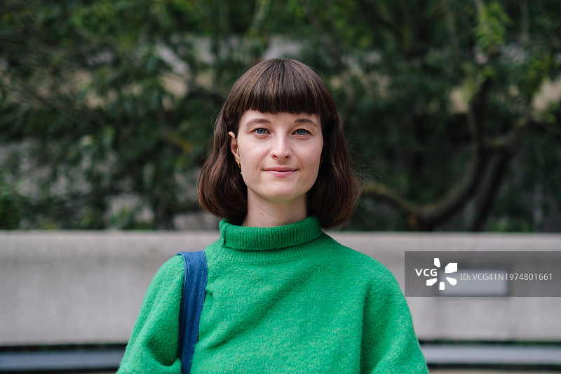 户外身穿绿色毛衣，自信微笑的休闲女子图片素材