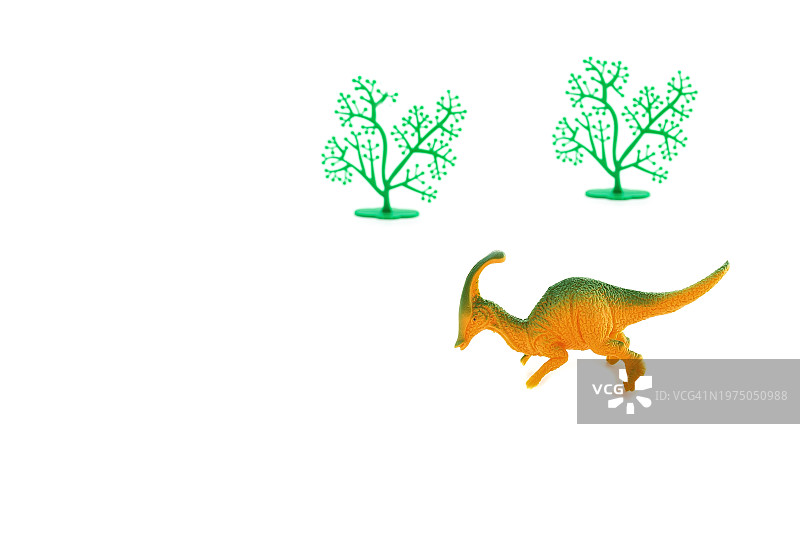 白色背景上的玩具恐龙和绿树图片素材