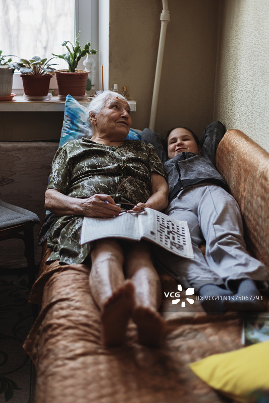 祖母和孙女躺在旧沙发上聊天图片素材