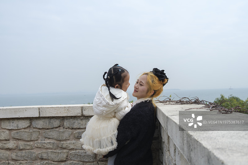 年轻的亚洲母亲拥抱亲吻女儿的背影图片素材