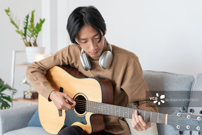 亚洲年轻男子在客厅弹吉他图片素材