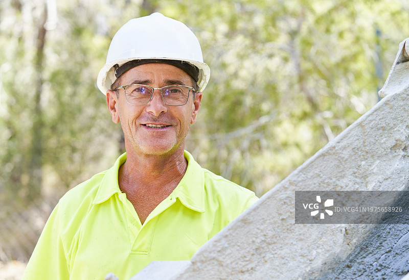 佩戴头盔和眼镜的男工程师正面肖像，面带微笑看着镜头图片素材