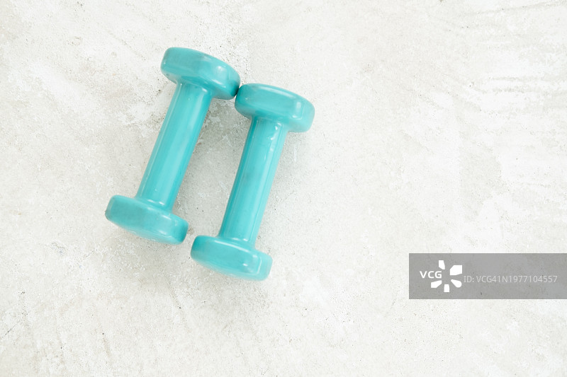 白色水泥地面上的蓝色哑铃俯视图片素材