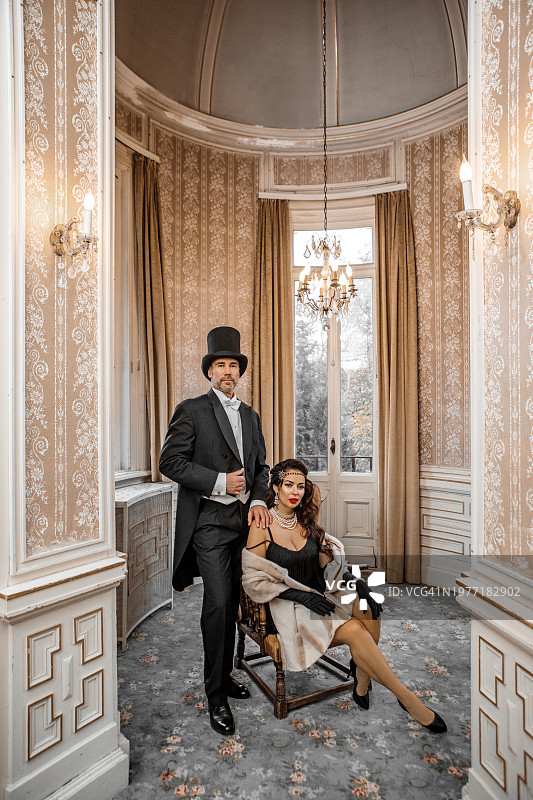 豪宅中男伴陪同的1920年代风格的漂亮黑发女子图片素材