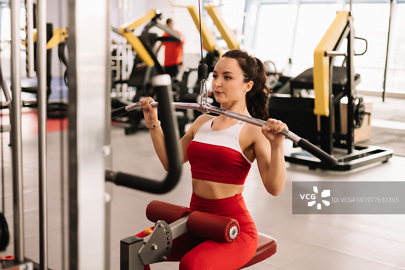 在健身房使用哑铃和跑步机进行训练的健美女性图片素材