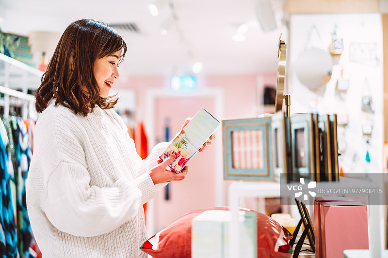 漂亮的亚洲女人在购物中心的家居香氛店购物图片素材