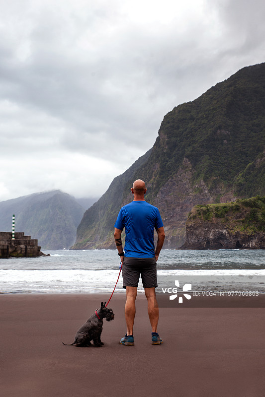 男子带着狗看着大海图片素材