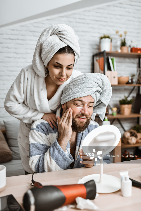 女人鼓励男友在脸上涂抹护肤霜图片素材