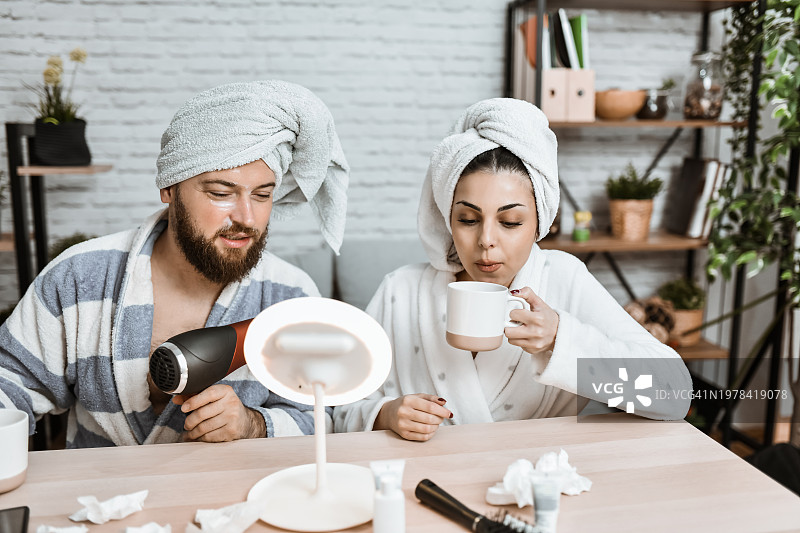 女性喝茶，男友吹干头发图片素材