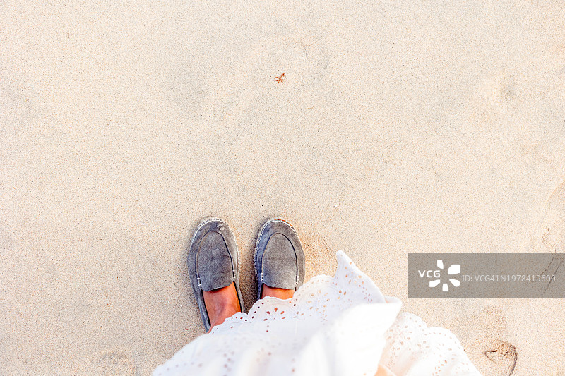 女士穿着草底鞋站在沙滩上图片素材