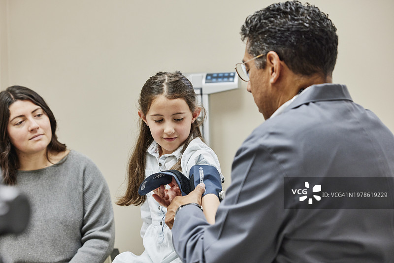 医生在检查期间为病人戴上血压袖套的半身照图片素材