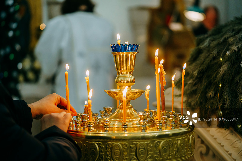 圣诞节在东正教教堂点燃蜡烛的女人图片素材