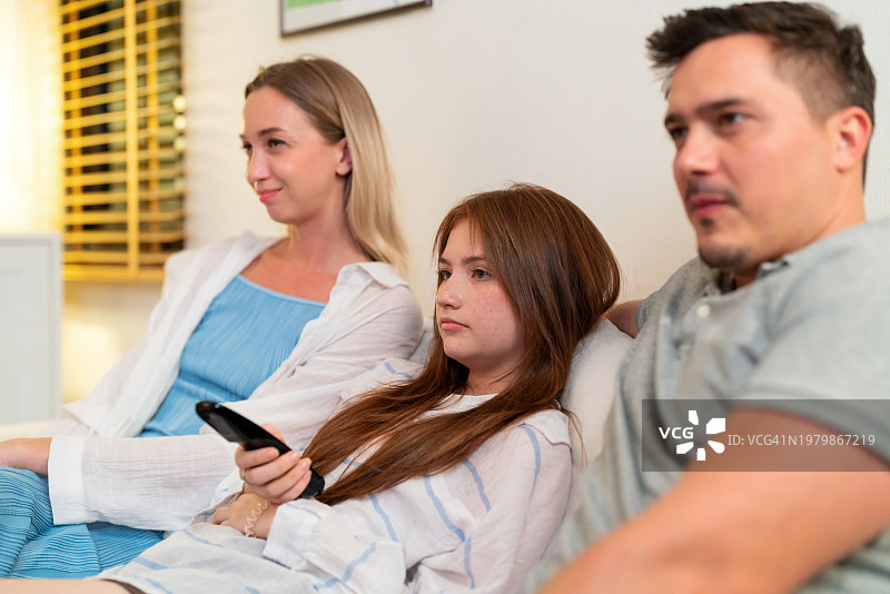 一家人围坐在一起看电视，共享欢乐时光，品尝爆米花，充满欢声笑语图片素材